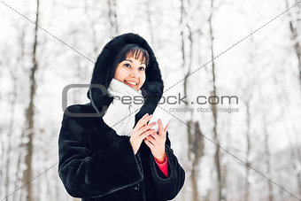 Young woman smiling with smart phone and winter landscape