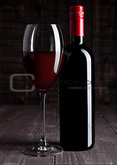 Bottle and glass of red wine on wooden board 