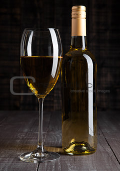 Bottle and glass of white wine on wooden board 
