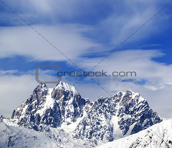 Mounts Ushba and Chatyn and blue sky with clouds in winter wind 