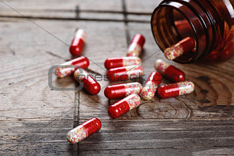 Pill bottle and capsules on wooden table