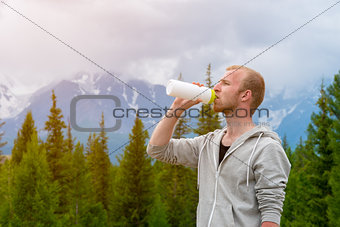 Men runner drinking water outdoors. Mountains background.