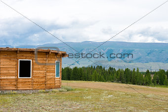 Wooden mountain house on green field. Mountains, Altay, Russia.