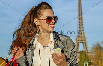 woman with shopping bags and smartphone in Paris looking aside