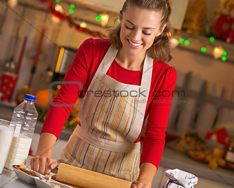 Happy young housewife rolling pin dough in christmas decorated k