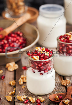 Fresh yogurt with pomegranate seeds and walnut in a glass jars