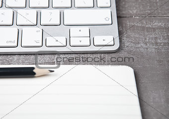 Keyboard with pencil on open notebook sheet 