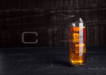 Glass of cola soda with ice cubes on wooden board
