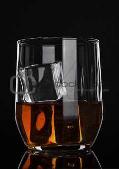 Glass of whiskey with ice on wooden background