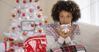 Pretty woman sipping from cup while seated on sofa