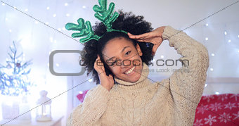 Playful young woman wearing green reindeer antlers