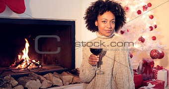 Pretty woman holds wine glass beside fireplace