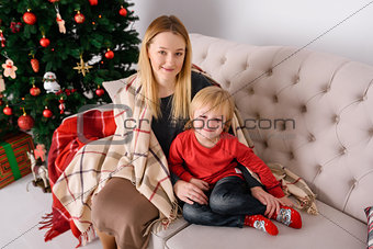 Mother and son sitting near a rug covered trees