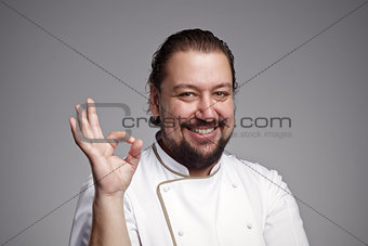 Pleased chef looking confidently at the camera, showing sign oka