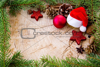 Christmas hat with bauble and fir branches on wood background.