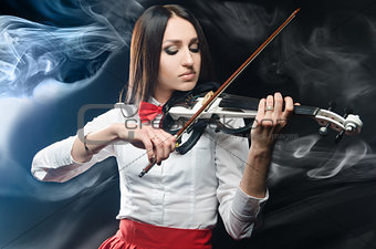 Dreamy woman playing the violin on a black background