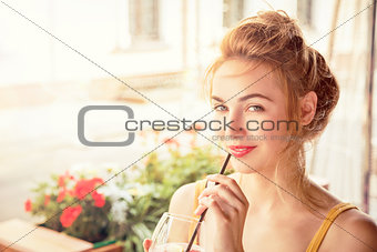 Smiling Fashion Girl Drinking Cocktail in a Cafe