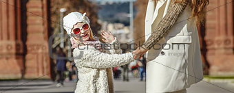 mother and child near Arc de Triomf in Barcelona handwaving