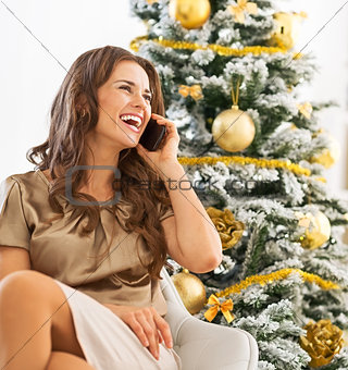 Portrait of happy young woman talking cell phone while sitting n