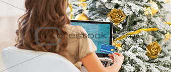 Woman with credit card and laptop in front of christmas tree