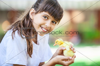 Smiling girl with a spring duckling