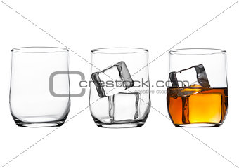 Glasses with whiskey and ice cubes and empty glass