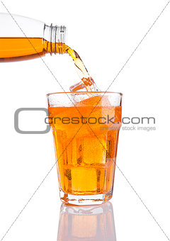 Pouring orange energy soda drink in glass with ice