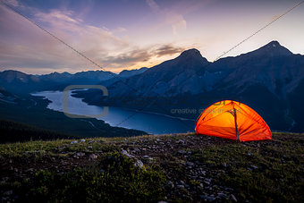 Glowing tent set up on a ridge for camping in the mountains