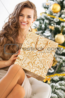 Happy young woman with shopping bag near christmas tree