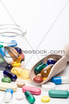 Color pills in glass container and wooden dispencer portrait