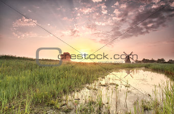 beautiful summer sunrise over windmill by river