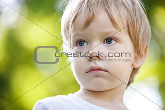 Portrait of a cute boy in a pensive mood against green background