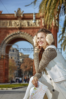 happy trendy woman in earmuffs in Barcelona, Spain with map