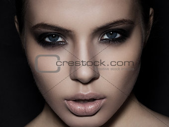 Beautiful woman model smokey eyes makeup closeup on black