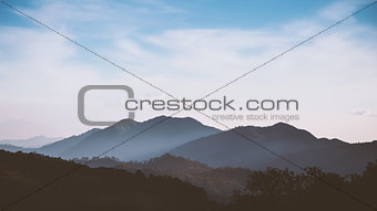 Foggy mountain range with cloudy blue sky