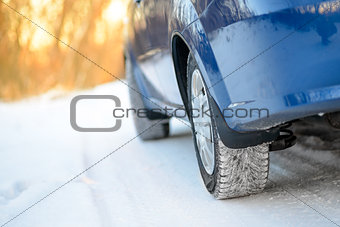 Close-up Image of Winter Car Wheel on Snowy Road. Drive Safe Concept.