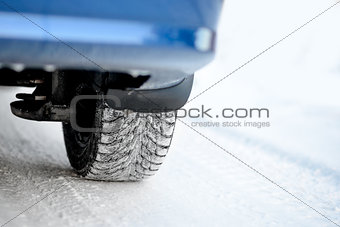 Close-up Image of Winter Car Tire on Snowy Road. Drive Safe Concept.