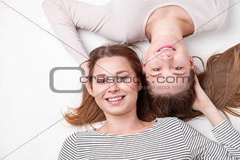 Portrait of happy sisters lying on the floor 
