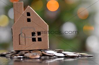 Model of house with coins on wooden table