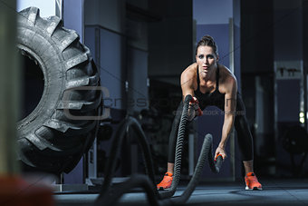 Powerful attractive muscular Fitness trainer do battle workout with ropes