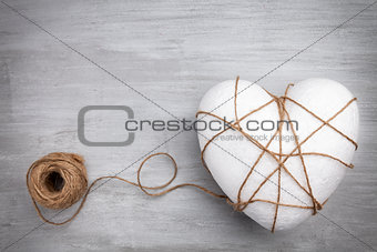 Heart bound by a string on grey background