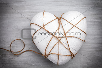 Heart bound by a string on grey background