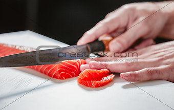 Close up on slicing raw salmon with sharp knife