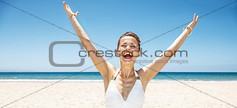 Happy woman in swimsuit at sandy beach on sunny day rejoicing