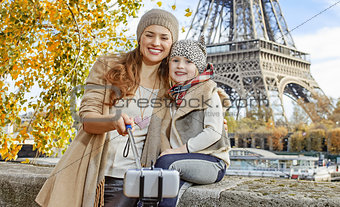 mother and child travellers taking selfie on embankment in Paris