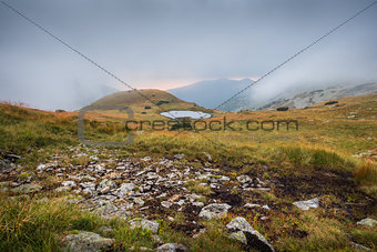 Foggy Mountain Landscape with a Tarn at Sunset