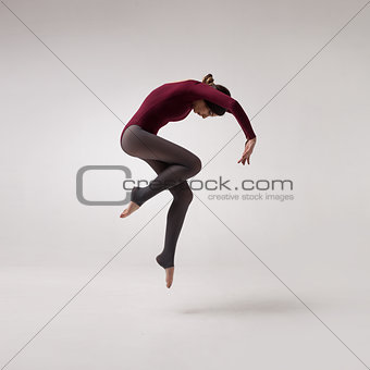 young woman dancer in maroon swimsuit jumping