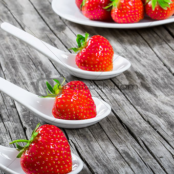strawberries on a porcelain spoons on an old rustic table