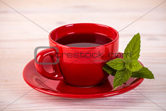 Red cup of tea with green leaves