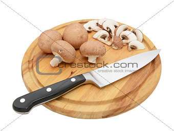 Knife with whole chestnut mushrooms and slices on board
